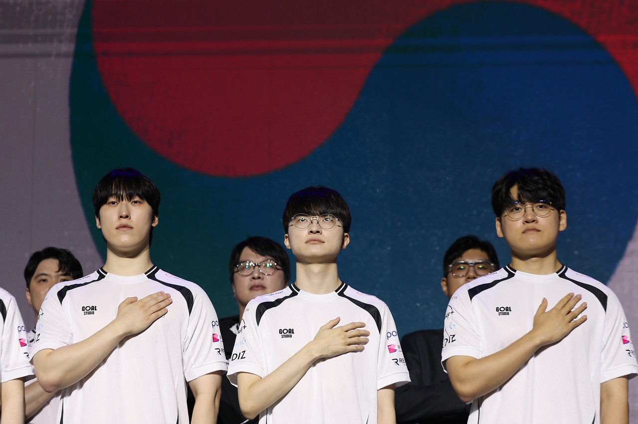 From left: Kim "Zeka" Geon-woo, Lee "Faker" Sang-hyeok and Lee "Gumayusi" Min-hyeong salute during a press event held in Seoul on Tuesday. (Yonhap)