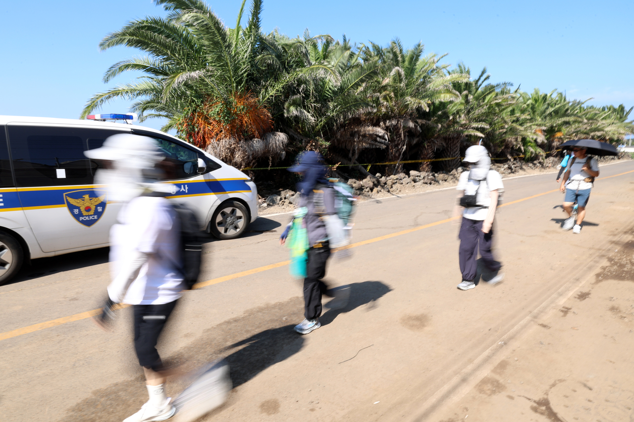 Hikers walk past a palm tree farm in Hallim-eup, on Wednesday, where the body of Jang Mi-ran, a 37-year-old reported missing in May, was found. (Yonhap)