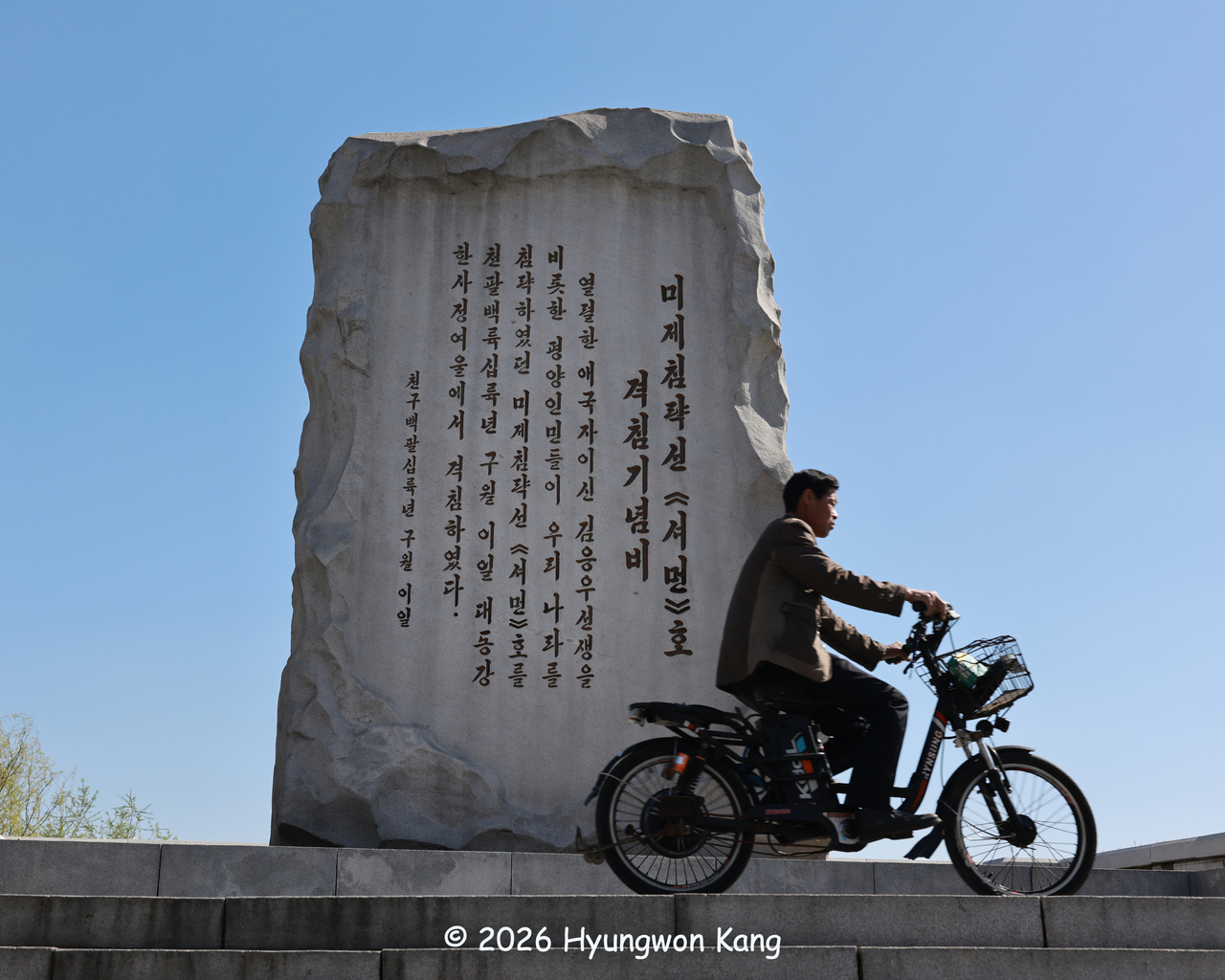 A man rides an electric bicycle past the Monument to the Sinking of the General Sherman along the Taedonggang River in Pyongyang on April 15.
The inscription on the front reads: Monument to the Sinking of the US Imperialist Aggressor Ship Sherman “On Sept. 2, 1866, the people of Pyongyang, including the ardent patriot Kim Ung-u, sank the US imperialist aggressor ship Sherman, which had invaded our country, at Hansajong Rapids on the Taedong River.” (Hyungwon Kang)