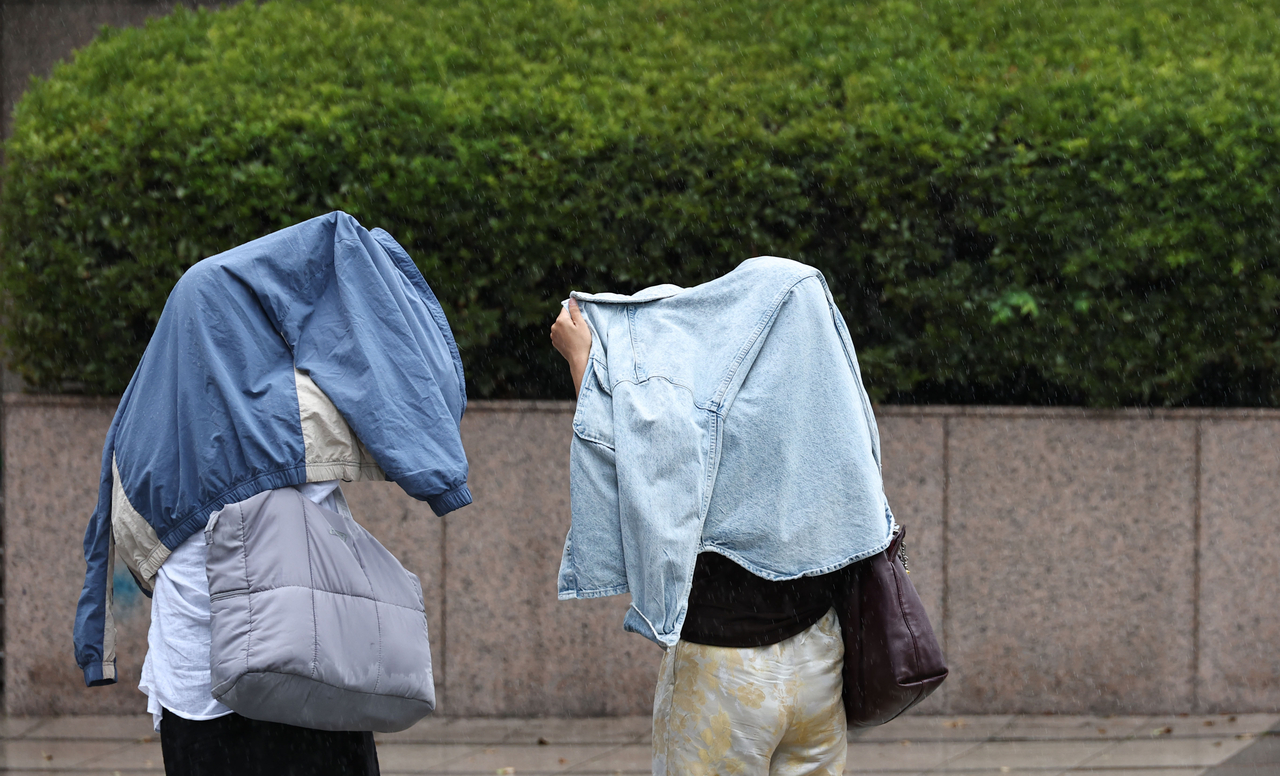 People dodge a sudden rain shower at Cheonggye Plaza in Seoul on Aug. 17. (Yonhap)