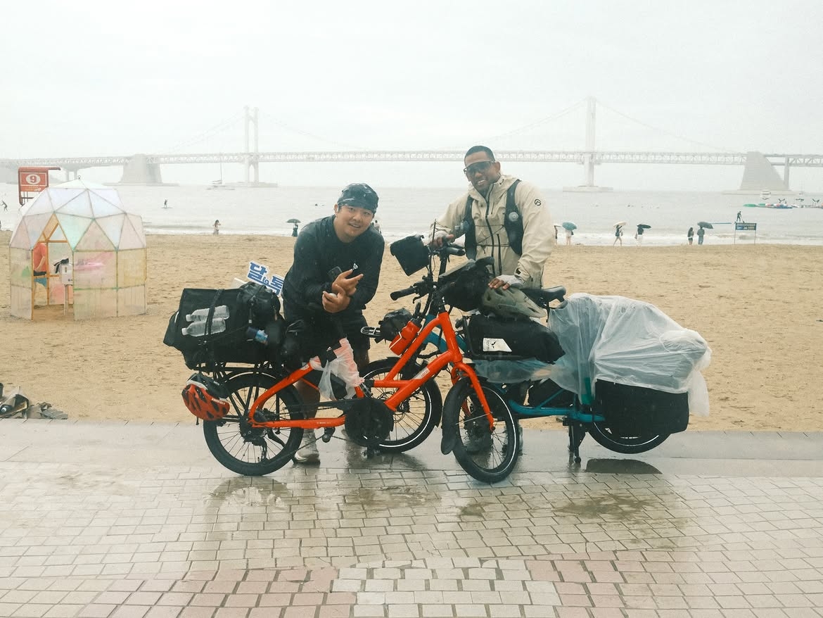 Kim Woo-jin (left) and Emile Justin Appollis, who accompanied Zay, pose for a photo. The duo followed along on e-bikes to film his journey and carry supplies. (Instagram @movezay)
