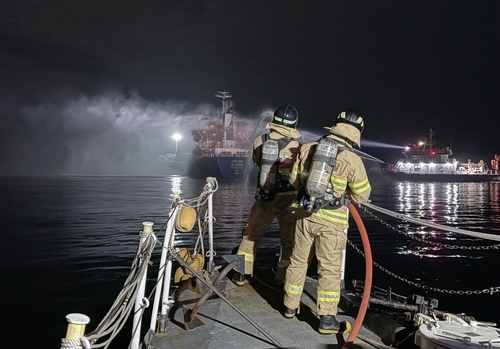 Officials taking part in firefighting efforts after a fire broke out aboard a ship carrying oil products in waters off Incheon, on Friday. (Yonhap)