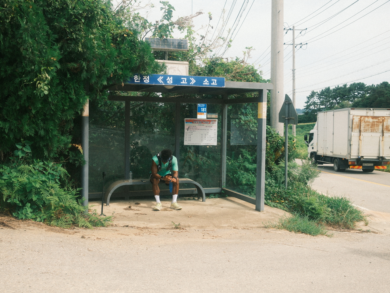 Zay takes a break at a rural bus stop during his run from Seoul to Busan. (Emile Justin Appollis, Kim Woo-jin)