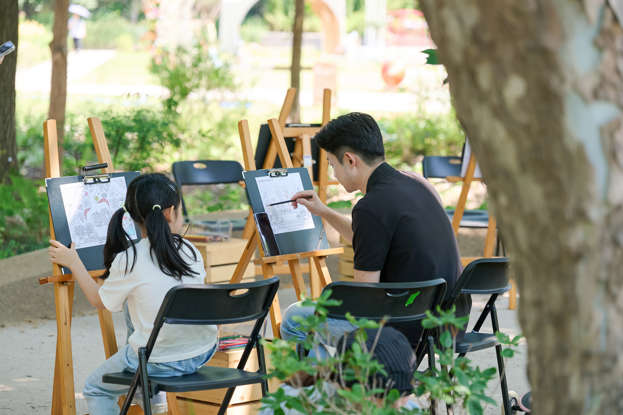 A family taking part in the coloring class fills in a garden illustration at the learning garden. [GS Caltex]
