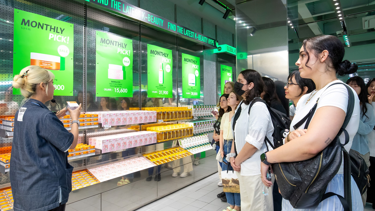 Customers crowd around as a staff member explains Korean skincare products at an Olive Young store in Seoul. (CJ Olive Young)