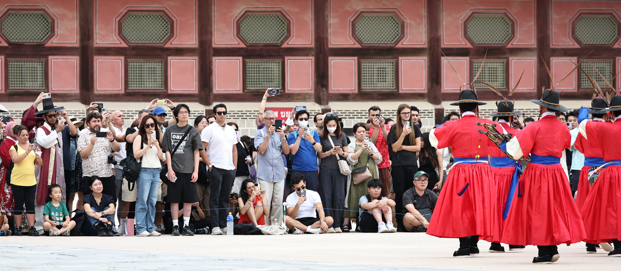Visitors watch the changing of the guard ceremony at Gwanghwamun in central Seoul on Sunday. (Yonhap)