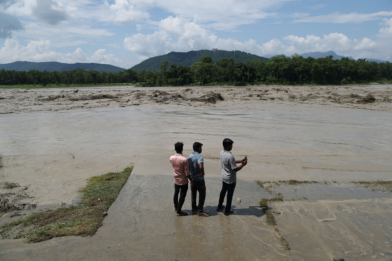 People look at muddy water along the Narayani River in Chitwan, Nepal, Sunday, as recovery efforts continue following massive flooding in the Himalayan region along the Nepal-China border, more than 100 kilometers from the site of the initial accident. (Yonhap)