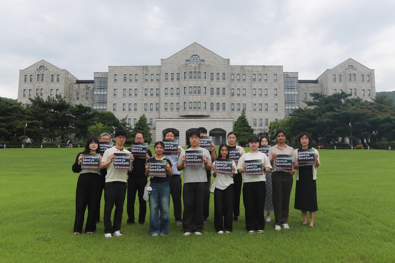 Korean and Nepali students and faculty at Hoseo University on Wednesday hold up placards promoting their fundraising campaign to support disaster recovery in Nepal following a massive flash flood. (Hoseo University)