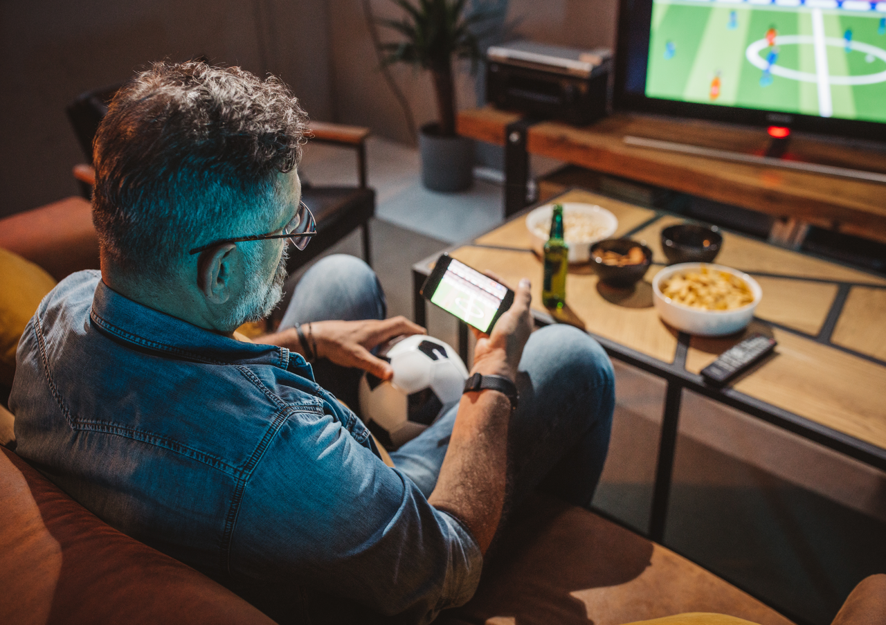 A man watches a soccer match on his smartphone. [Getty Images]