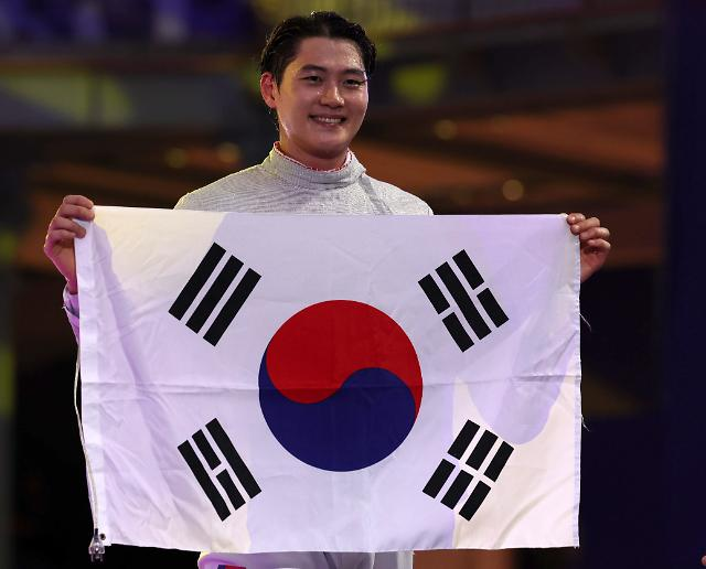 Fencing gold medalist Oh Sang-wuk holds up the South Korean flag at the 2024 Paris Olympics, with the red portion of its taegeuk symbol correctly curving toward the lower left. (Herald DB)