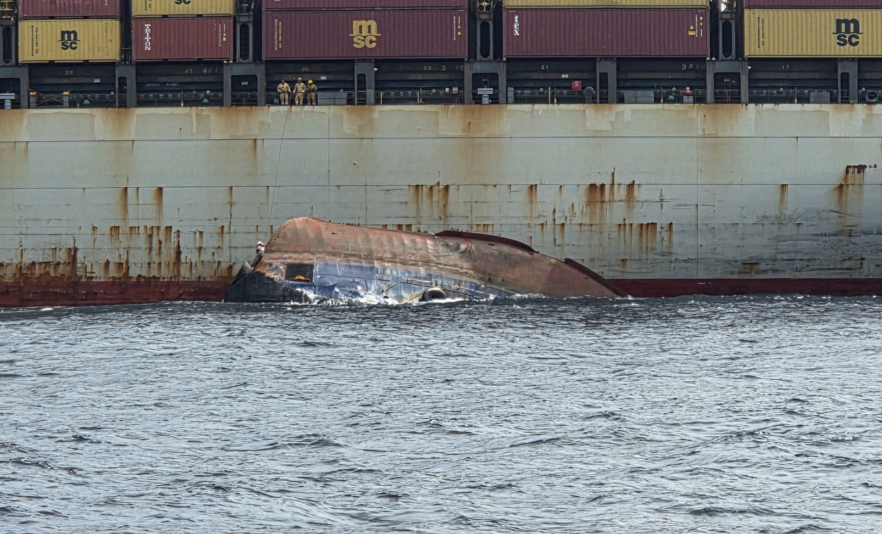 The coast guard conducts rescue operations after a tugboat capsized off Busan on Wednesday afternoon. The overturned vessel is visible at the scene as a passing cargo ship assists in the rescue effort. [Busan Maritime Police Station/Yonhap]