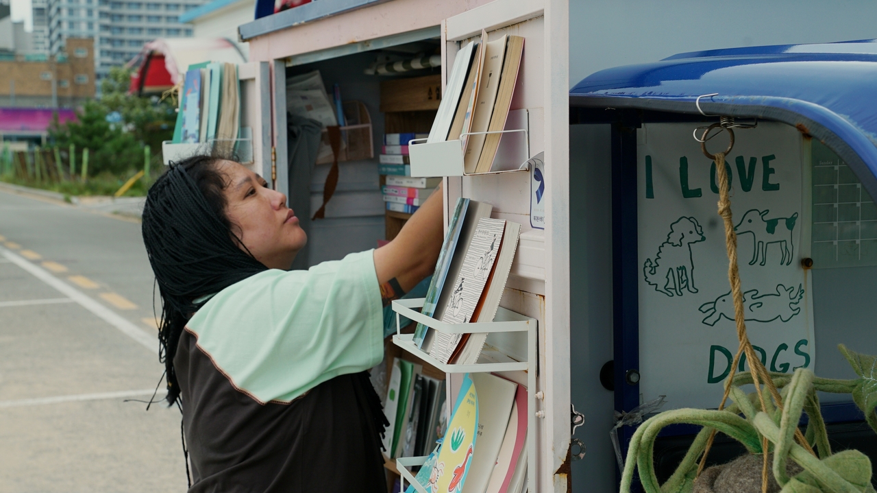 Park Young-ah, owner of Three Feet Bookstore, tidies up a bookshelf in Sokcho, Gangwon Province on Aug. 26 (Song Seung-hyun/The Korea Herald)