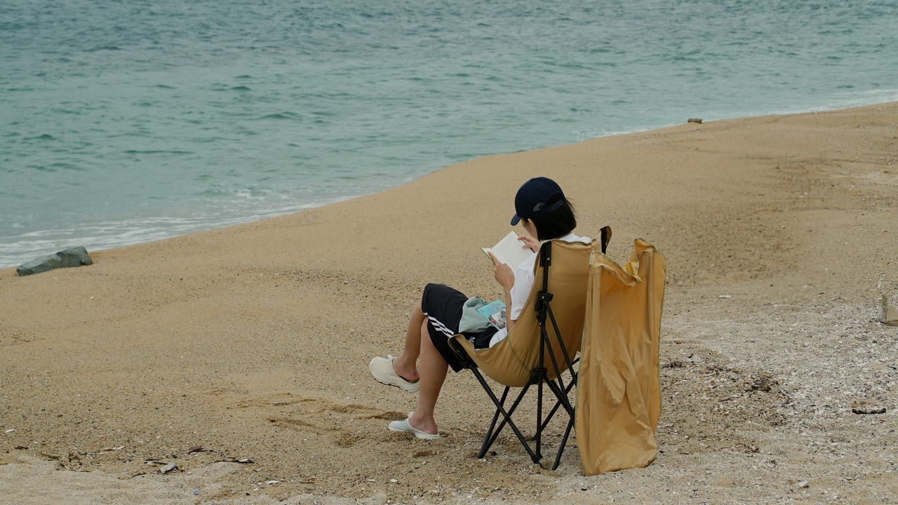 Kim Seul-gi, a woman in her 30s, reads at a beach in Sokcho, Gangwon Province, on Aug. 26. (Song Seung-hyun/The Korea Herald)