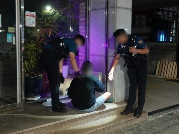 Police officers escort an intoxicated person found sleeping on the street during a patrol. This photo is unrelated to the article. [Newsis]