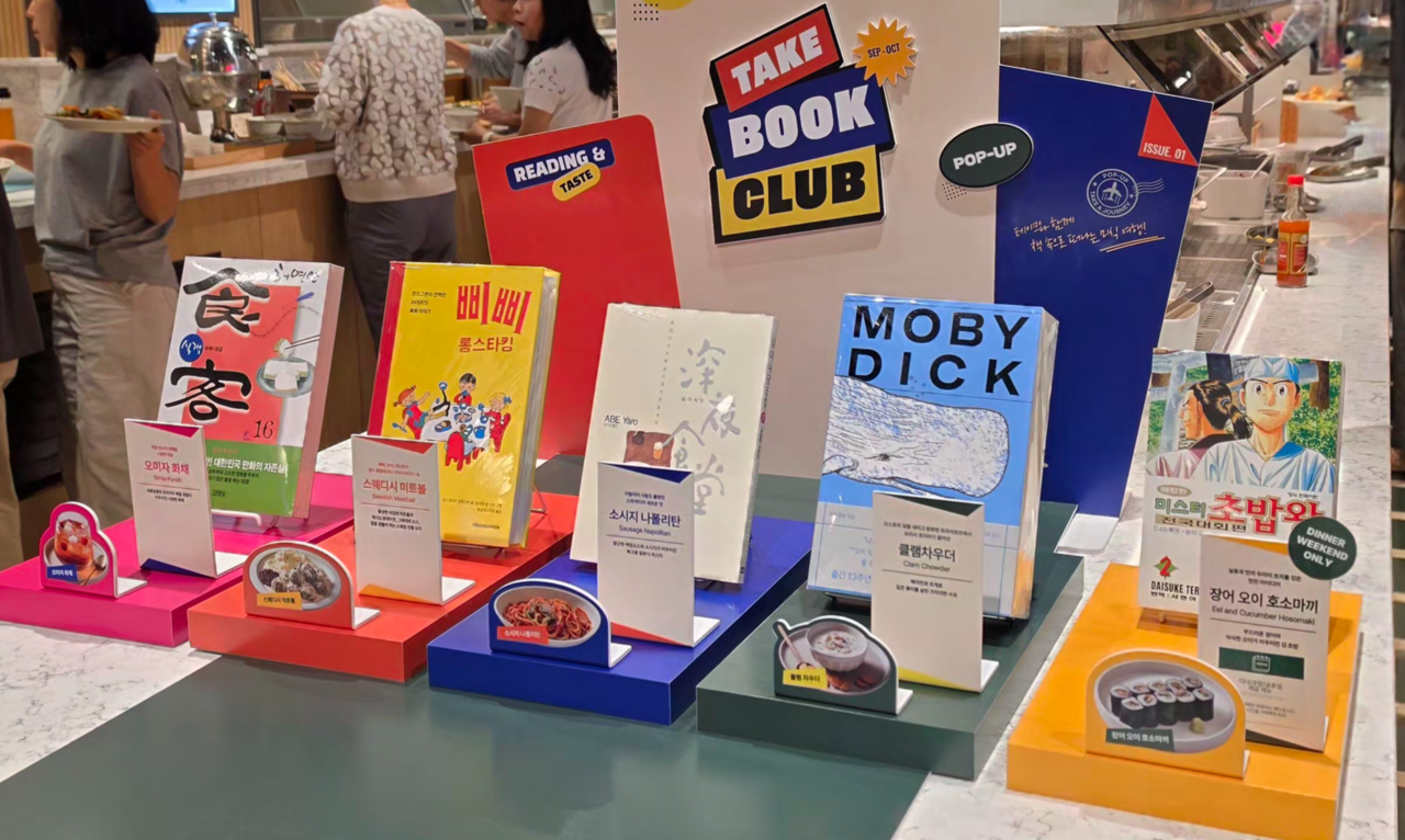 Take, the buffet brand of food service company Ourhome, is running a "TAKE BOOK CLUB" pop-up table in collaboration with Youngpoong Bookstore through Nov. 10, offering menu items reimagined from literary works. The photo shows a corner introducing the Youngpoong Bookstore collaboration menu at the Take Jonggak branch on Friday. [Ourhome]