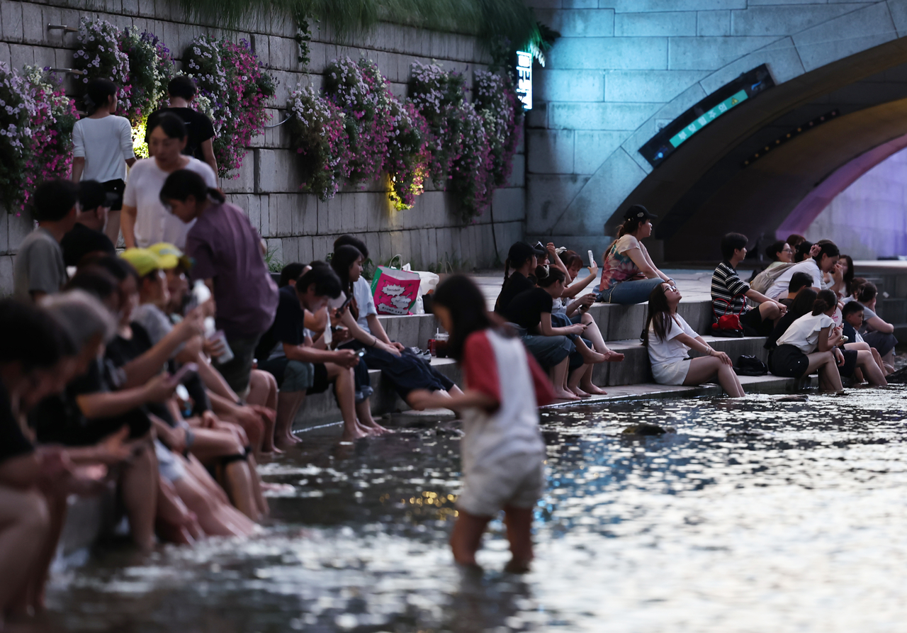 People cool off along Cheonggye Stream in central Seoul on Aug. 4. (Yonhap)