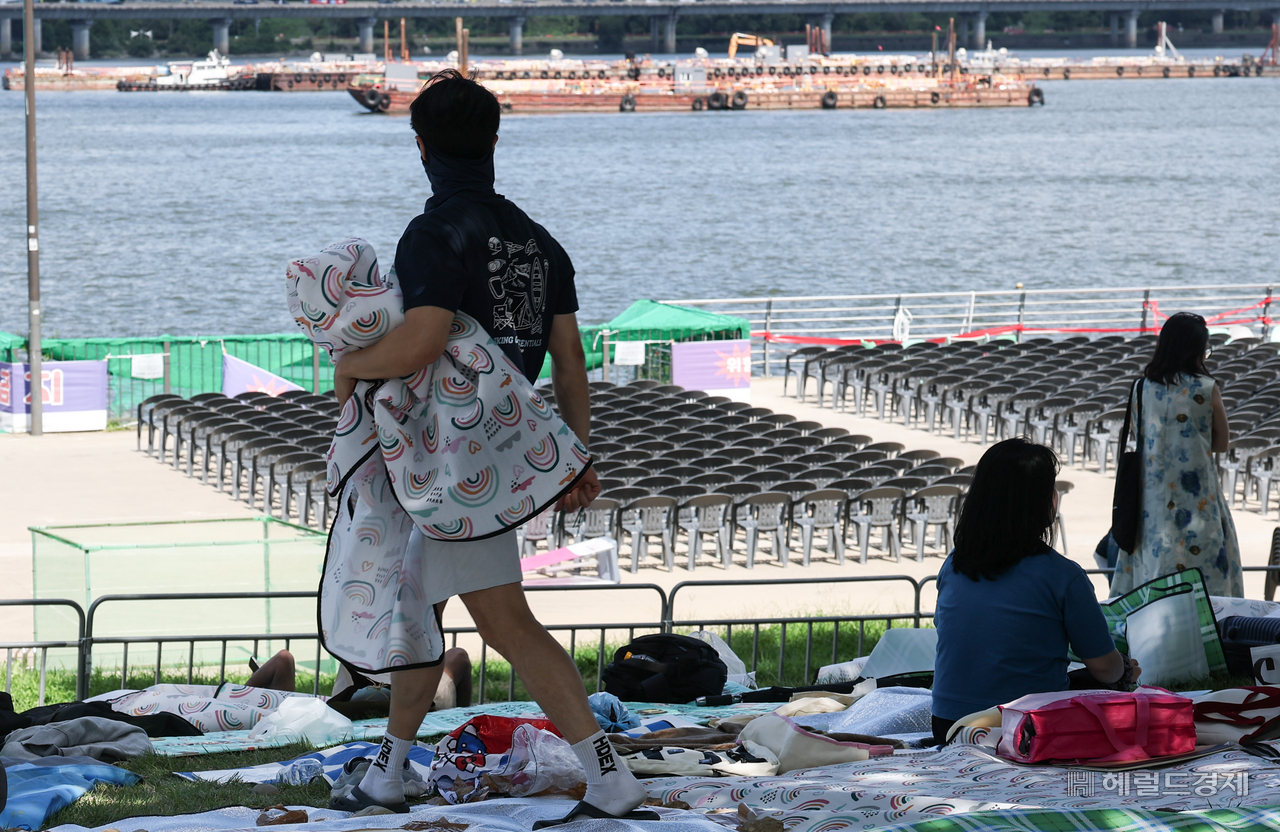 A visitor carries a mat to claim a prime viewing spot at Yeouido Hangang Park in Yeongdeungpo-gu, Seoul, on Friday, the day before the Seoul International Fireworks Festival 2026. (Yoon Chang-bin)