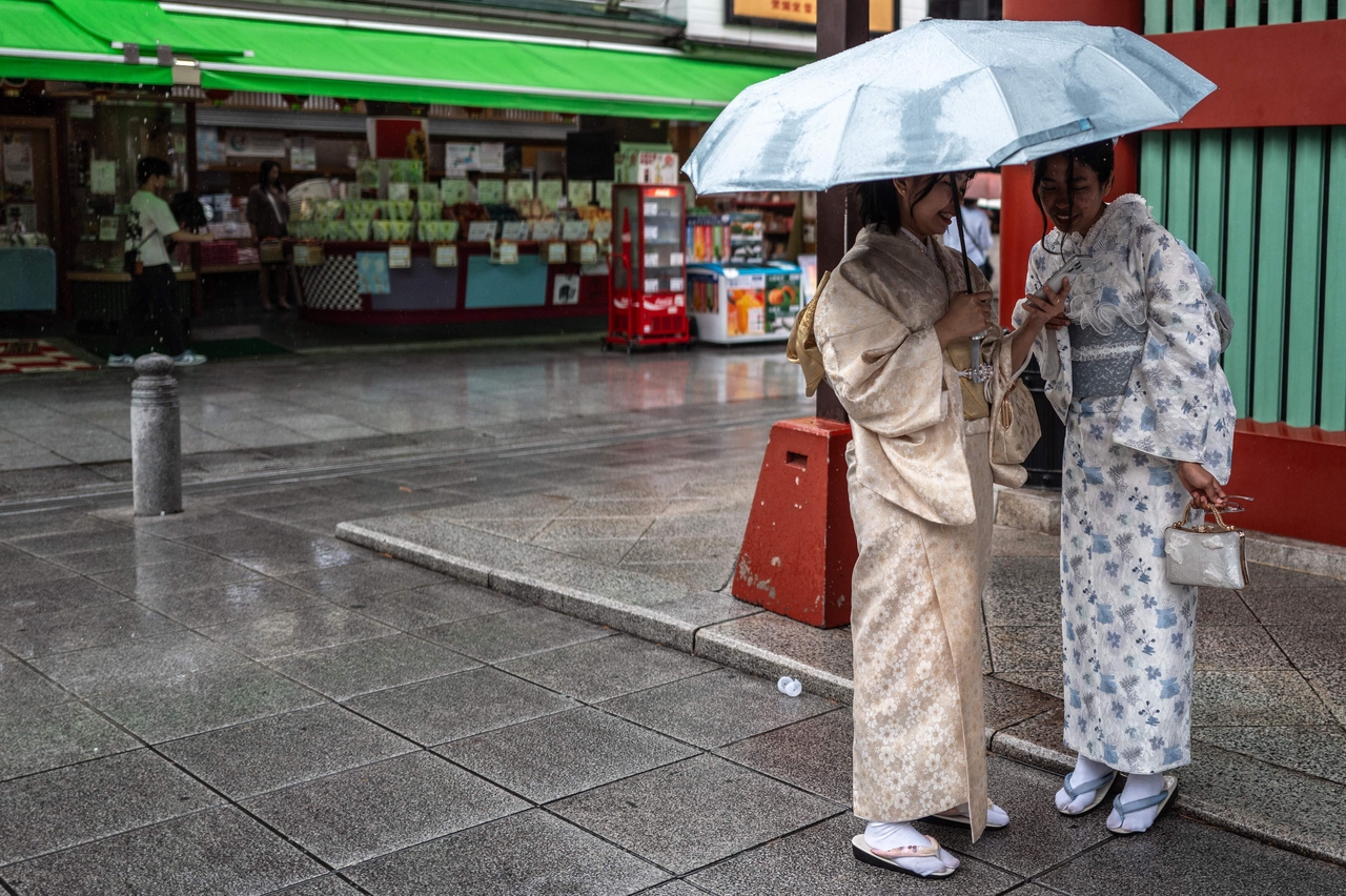 Foreign tourists in kimono chat on the street leading to Senso-ji temple in the Asakusa district of Tokyo. [AFP]
