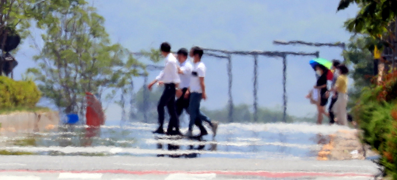 Pedestrians in Sejong's Eojin-dong are obscured by intense heat rising from the road surface. [Newsis]