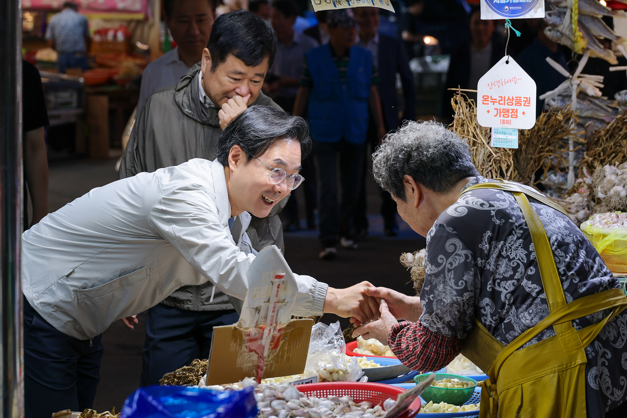 Dongdaemun-gu District Mayor Choi Dong-min greets an elderly merchant during a market visit.