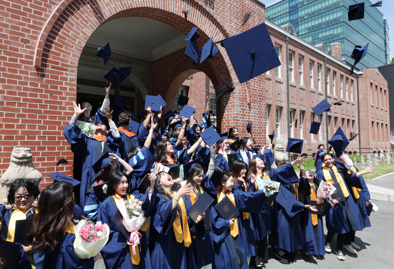 International students at Dong-A University in Busan toss their graduation caps following a commencement ceremony on Aug. 20. (Yonhap)