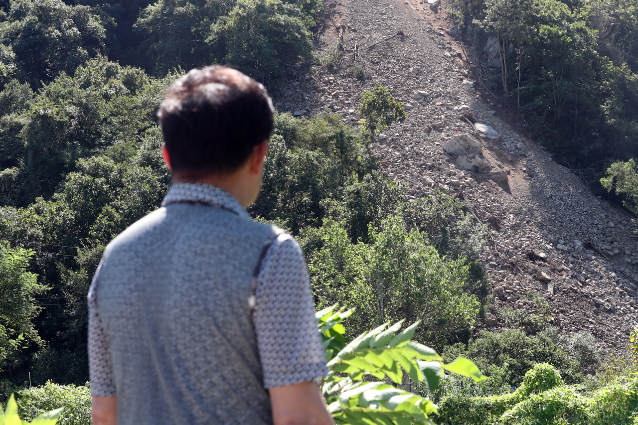 A resident looks at rocks and soil sliding down a slope in Hongcheon-gun, Gangwon Province, Sept. 4. (Yonhap)