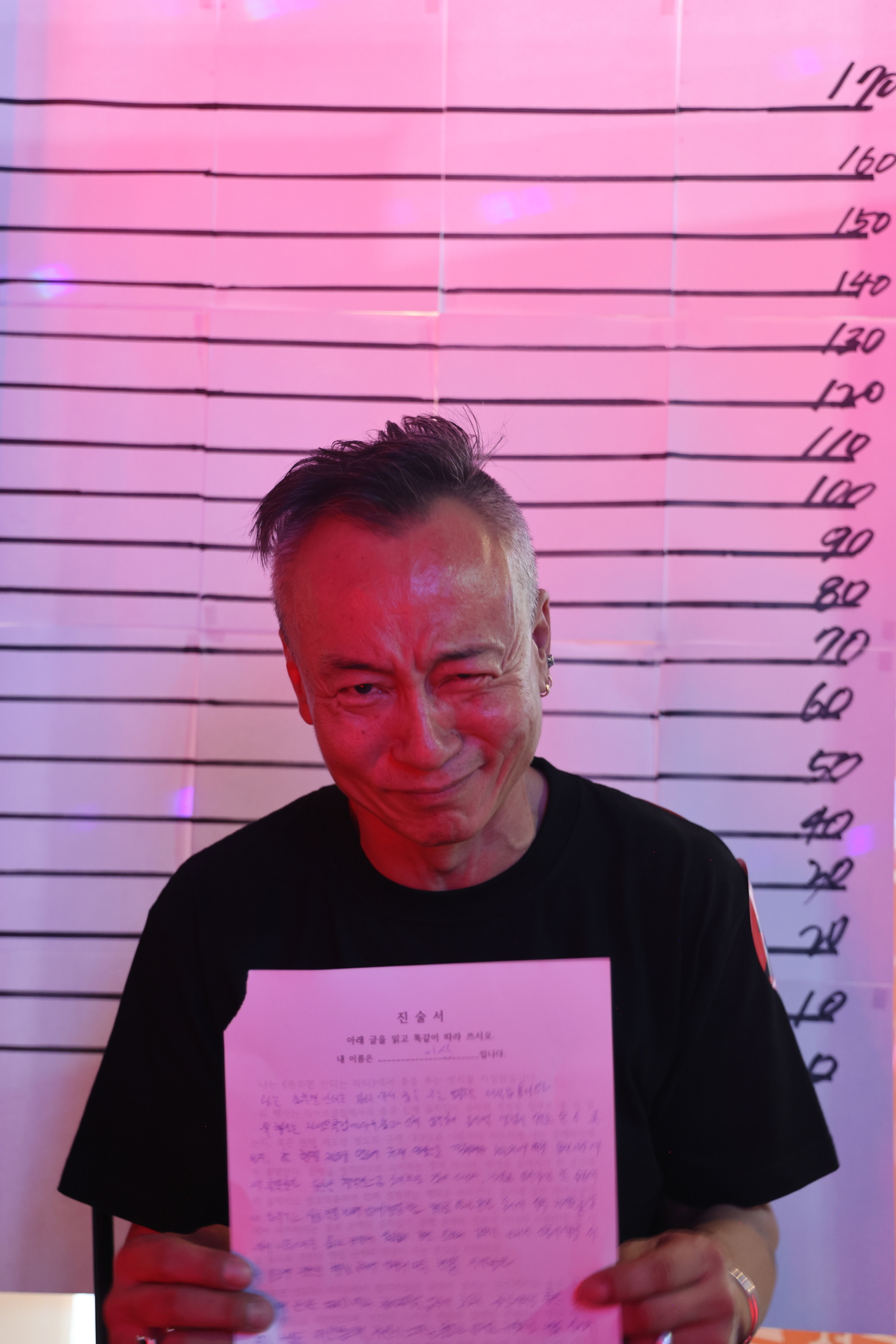 A participant poses for a mug shot with an apology letter after being caught dancing and locked in a mock jail as part of the rules for "Party Where You Can’t Dance,”  on Sept. 5. (Courtesy of Urban Strikers’ Jeonju branch)