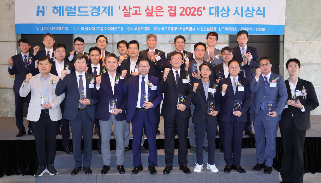 Attendees pose for a group photo at the Herald Business "Home of the Year 2026" awards ceremony held Friday morning at The Plaza hotel in Jung-gu, Seoul. From left in the back row: Kim Hyeong-gon, Herald executive managing director; Jeon Yeong-sam, Korea Housing Builders Association planning executive director; Park In-cheol, Kumho Engineering & Construction public relations and IR managing director; Kim Jae-sik, Korea Housing Association vice chairman; Kwon Hyeok-jin, Korea Federation of Construction Associations vice chairman; Kim I-tak, Ministry of Land, Infrastructure and Transport First Vice Minister; Choi Jin-young, Herald president; Lee Byeong-cheol, Seoul Metropolitan Government housing policy director; Kwon Nam-geun, Herald Business editor-in-chief; Park Jin-yu, BS Hanyang social media team leader; Oh Hae-jong, Jungheung Construction housing business division managing director; Jeong Sang-ryeong, DL E&C housing business division managing director; Park Baek-jin, Hanwha construction division design team deputy general manager; Kim Si-han, Hoban Construction housing and architecture business division head; Baek Un-ho, Hyundai E&C housing business division PD (managing director); Jeong Sang-ho, Daewoo Engineering housing business division managing director; Yang Mun-seok, GS Engineering & Construction public relations team managing director; Lee Sang-gi, Posco E&C Seoul project division head (managing director); Kim Jong-taek, Ipark Hyundai Development Iksan Busong Ipark site manager; Kang U-yeong, Lotte Engineering & Construction Ichon Le'El site manager; Gwak Jung-ho, Booyoung Group sales division director; Jo Gyeong-seop, Kukdong Engineering & Construction urban renewal division managing director; Lee Gyu-hwan, Korea Asset Purchase platform business service operations head.