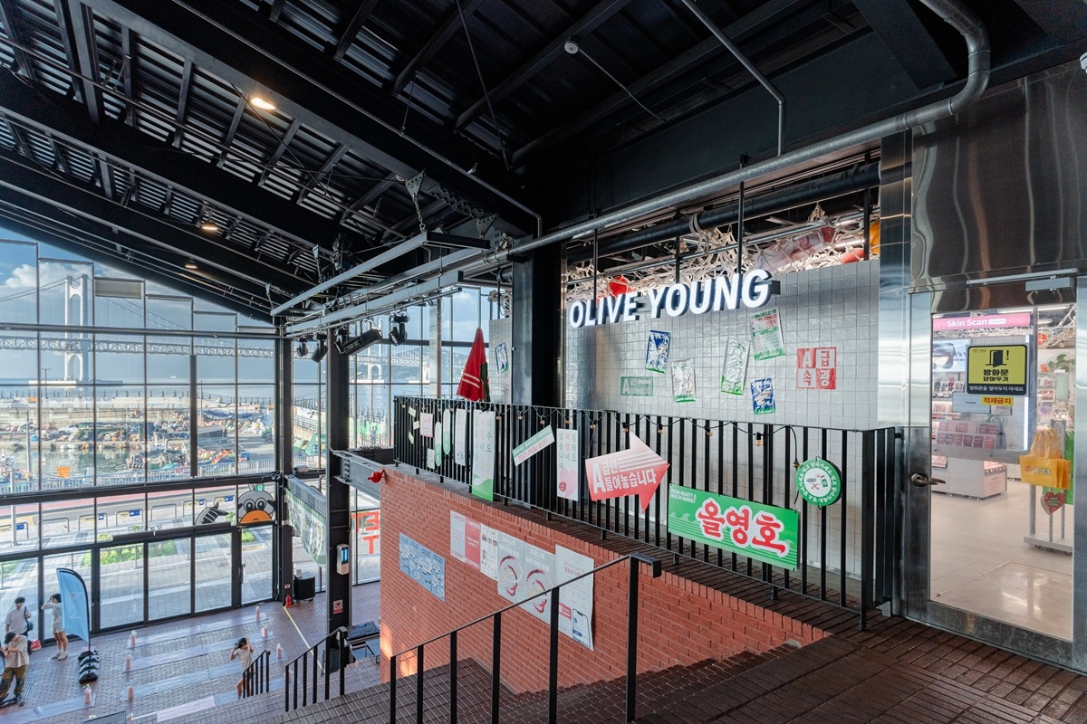 CJ Olive Young Millak the Market is a design-themed specialty store inside a mixed-use cultural complex. Built around the concept of the "Olive Young Ship" docked at Millak Port, the store features posters evoking a fresh-catch seafood market. [CJ Olive Young]