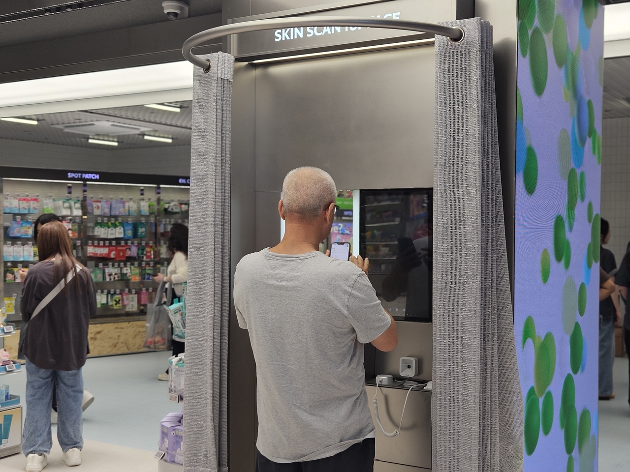 A foreign customer tries out a "Skin Scan for Face" skin-analysis device at CJ Olive Young Nampo Town on Friday morning. The store has six Skin Scan units in total, covering skin, scalp and color diagnostics. [Kim Jin]
