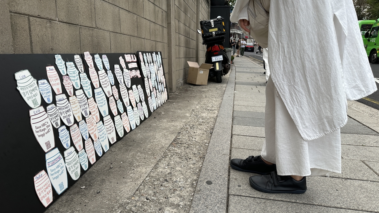 A passerby looks at the poster boards featuring paper onggi before signing one herself in Haebangchon, Yongsan-gu, Seoul, Sunday. (Tammy Park/The Korea Herald)