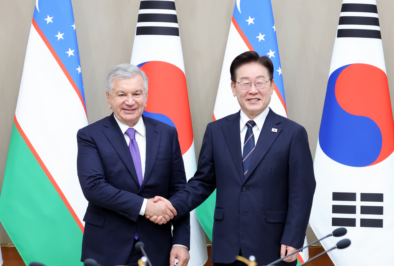 President Lee Jae Myung (right) and Uzbek President Shavkat Mirziyoyev shake hands ahead of an expanded summit at Cheong Wa Dae in Seoul on Monday. (Yonhap)