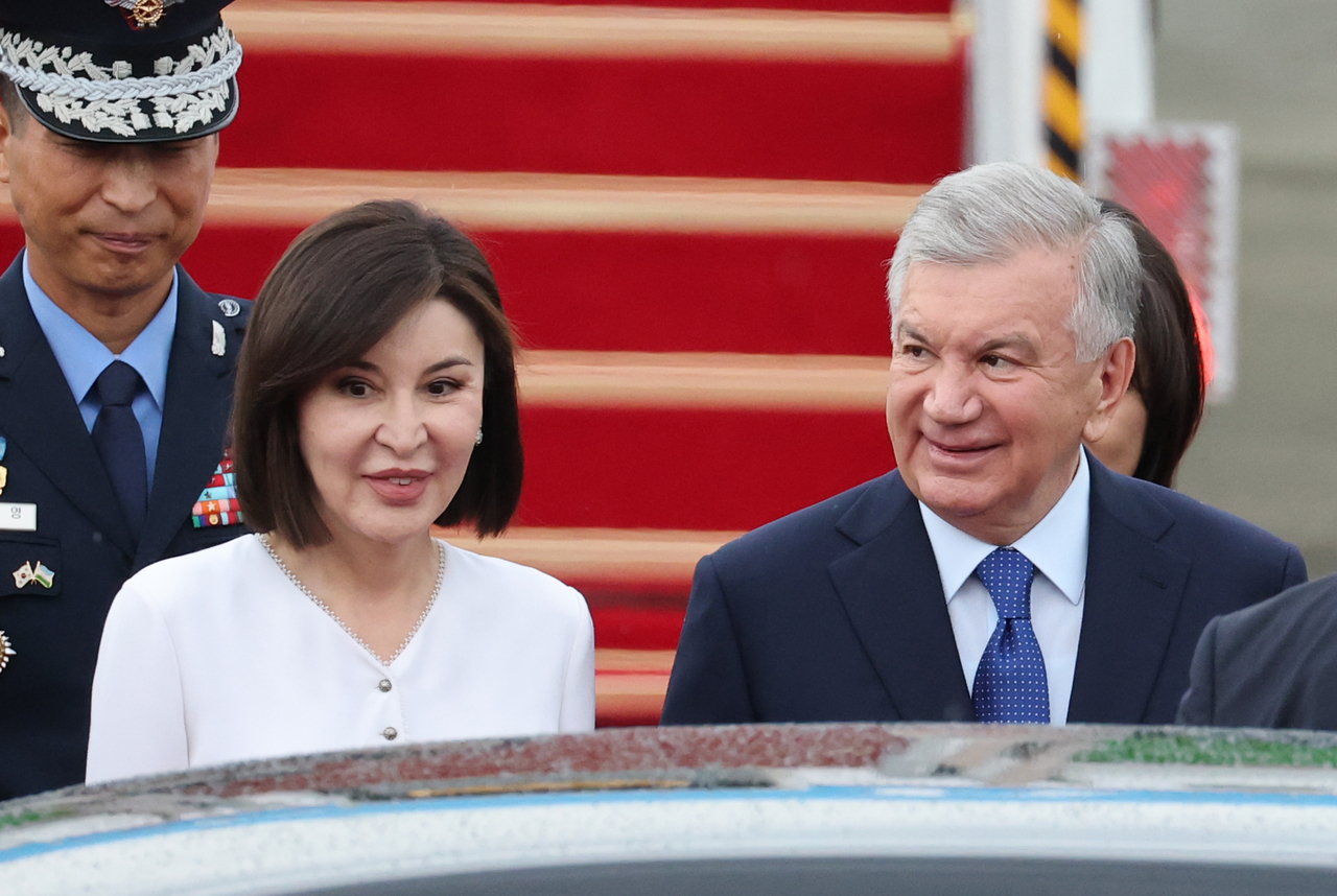 Uzbek President Shavkat Mirziyoyev and first lady Ziroat Mirziyoyeva walk after arriving at Seoul Air Base in Seongnam, south of Seoul, on Sunday. (Yonhap)
