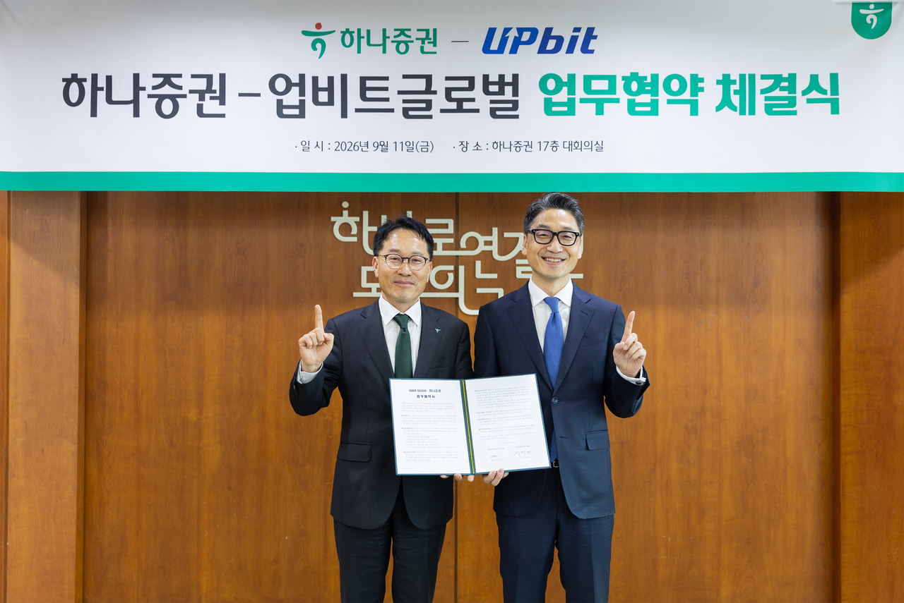Jung Young-kyun (left), head of Hana Securities' IB group, and Kim Guk-hyun, chief executive of Upbit Global, pose for a photo at the MOU signing ceremony for business cooperation in digital assets and finance on Friday. [Hana Securities]