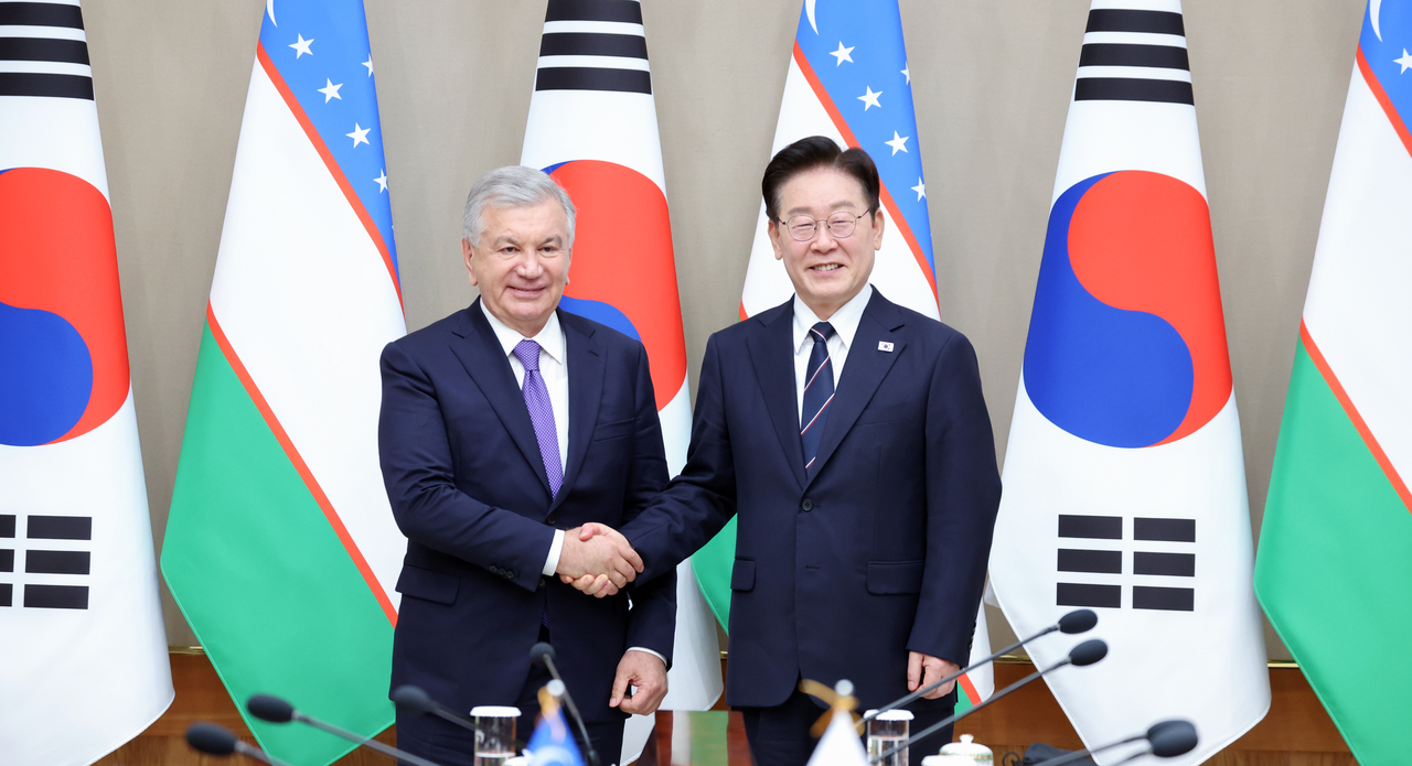 South Korean President Lee Jae Myung (right) and Uzbek President Shavkat Mirziyoyev shake hands on Monday  at Cheong Wa Dae. (Yonhap)