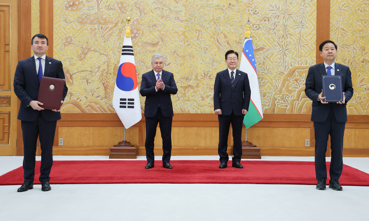 Ministry of Economy and Finance Minister Koo Yun-cheol and Uzbek Deputy Prime Minister Jamshid Khodjaev exchange MOU documents on the introduction of eight high-speed rail sets and the establishment of the national genomics and biobank center "Biome Center" at Cheong Wa Dae on Monday, in the presence of President Lee Jae Myung and Uzbek President Shavkat Mirziyoyev. [Yonhap]