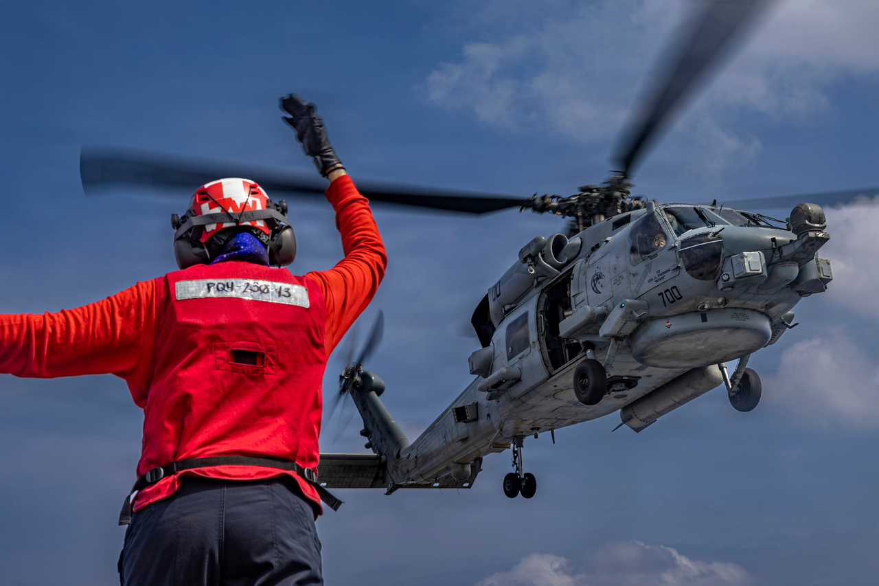 니미츠급 항공모함 USS 에이브러햄 링컨함 비행 갑판에서 한 항공병이 MH-60R 시호크 헬리콥터를 유도하고 있다. [AP]