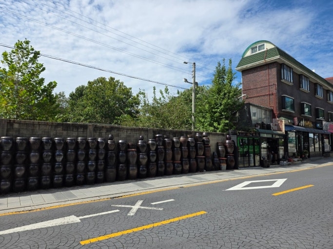 Rows of onggi stretch along the wall beside Hanshin Onggi in Haebangchon, Yongsan-gu, Seoul, before their recent removal. (Hanshin Onggi)
