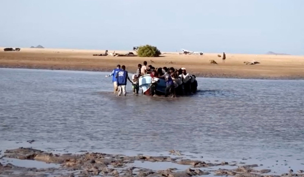 Staff walk towards a boat carrying refugees from Yemen, fleeing clashes between Houthi fighters and Saudi-backed Yemeni government forces, after arriving in Djibouti, September 12, 2026, in this screen grab taken from a video. (International Organization for Migration)