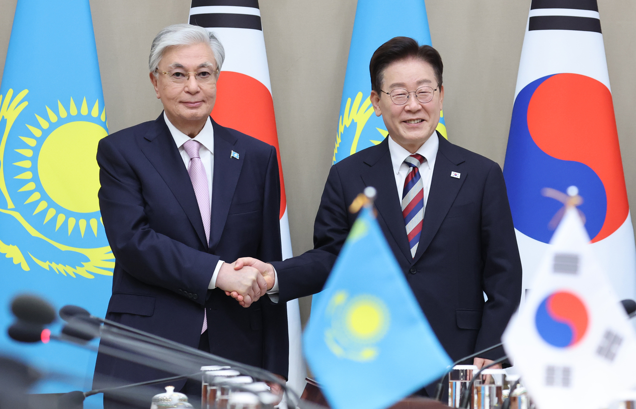 President Lee Jae Myung and Kazakh President Kassym-Jomart Tokayev shake hands at Cheong Wa Dae on Tuesday ahead of their expanded summit. (Yonhap)