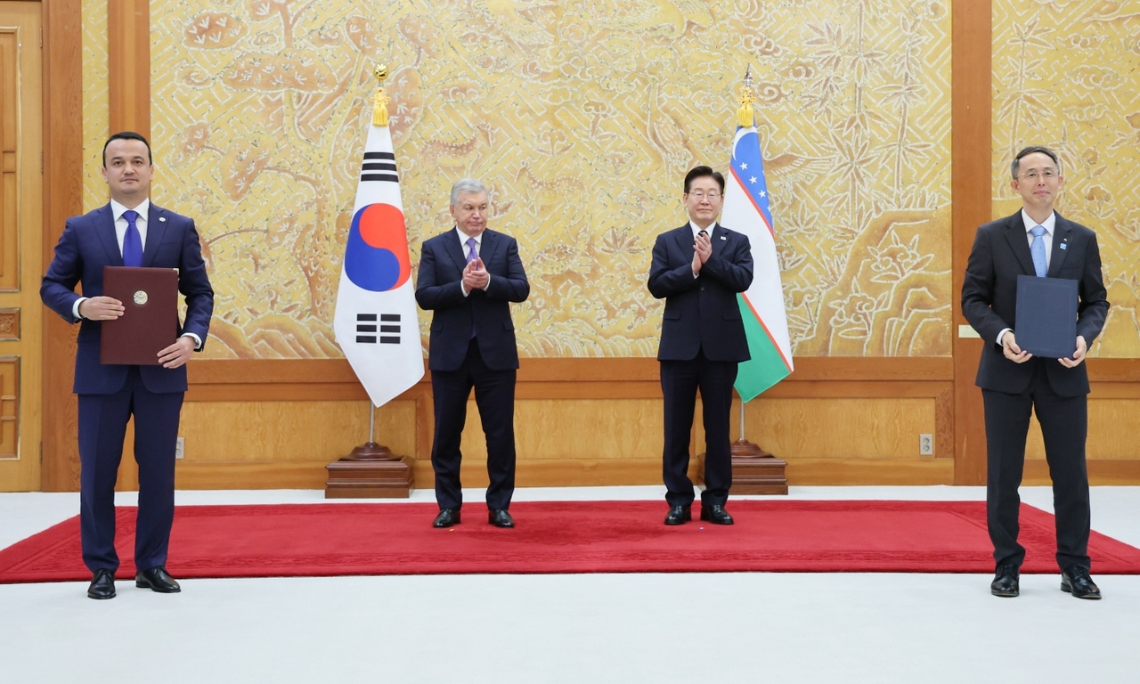 황기연 한국수출입은행장(사진 오른쪽)과 라지즈 쿠드라토프 우즈베키스탄 투자산업무역부장관이 14일 청와대에서 이재명 대통령과 샤브카트 미르지요예프 대통령이 임석한 가운데 전략적 사업발굴 체계 구축을 위한 양해각서 문건을 교환한 뒤 기념 촬영을 하고 있다.