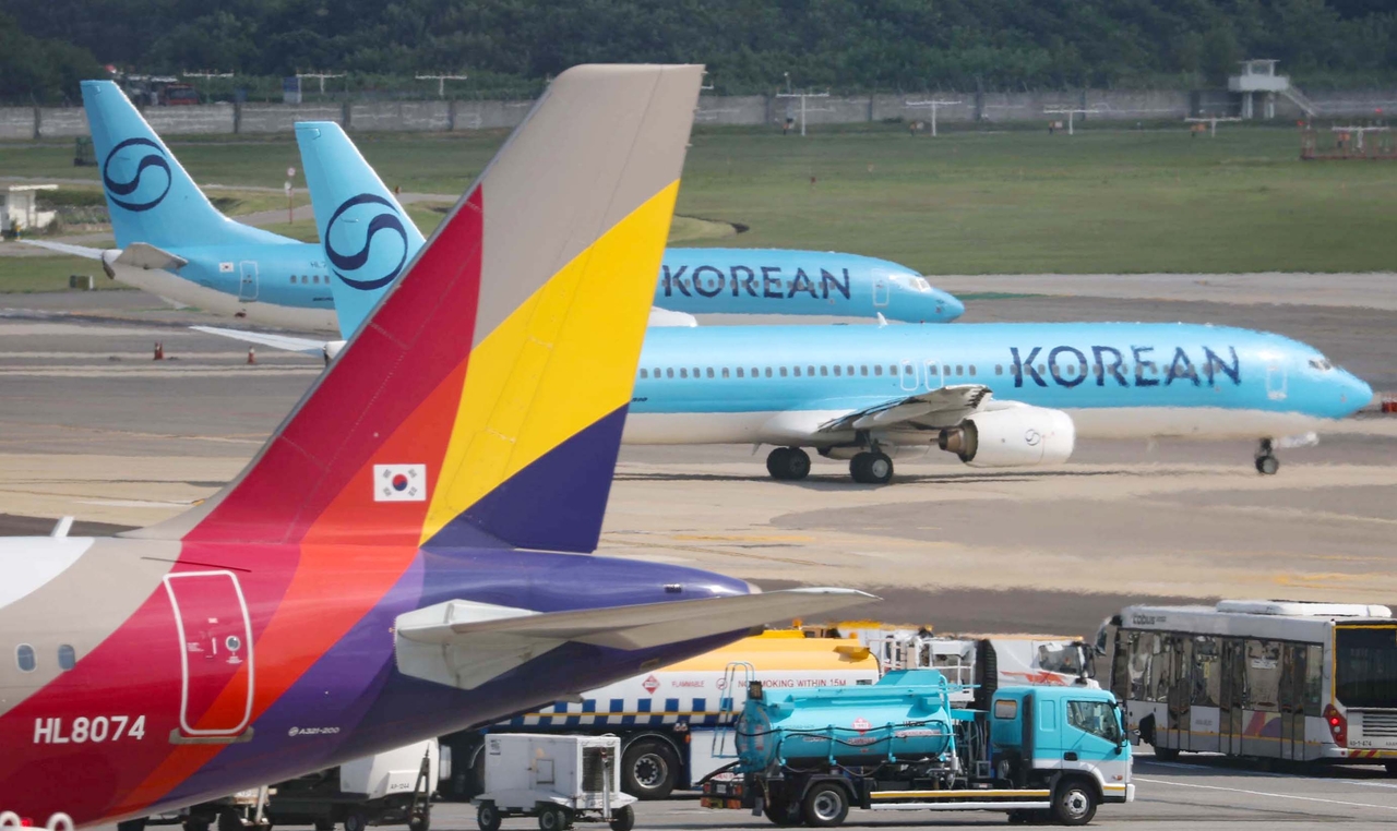 Korean Air and Asiana Airlines aircraft taxi across the apron at Gimpo Airport. [Yonhap]