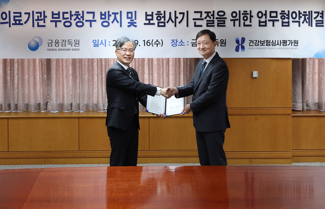 Health Insurance Review and Assessment Service President Hong Seung-kwon (left) and Financial Supervisory Service Director General Lee Chan-jin pose for a photo after signing an MOU on preventing improper billing by medical institutions and eradicating insurance fraud at the FSS headquarters in Yeouido, Seoul, on Wednesday. [Health Insurance Review and Assessment Service]