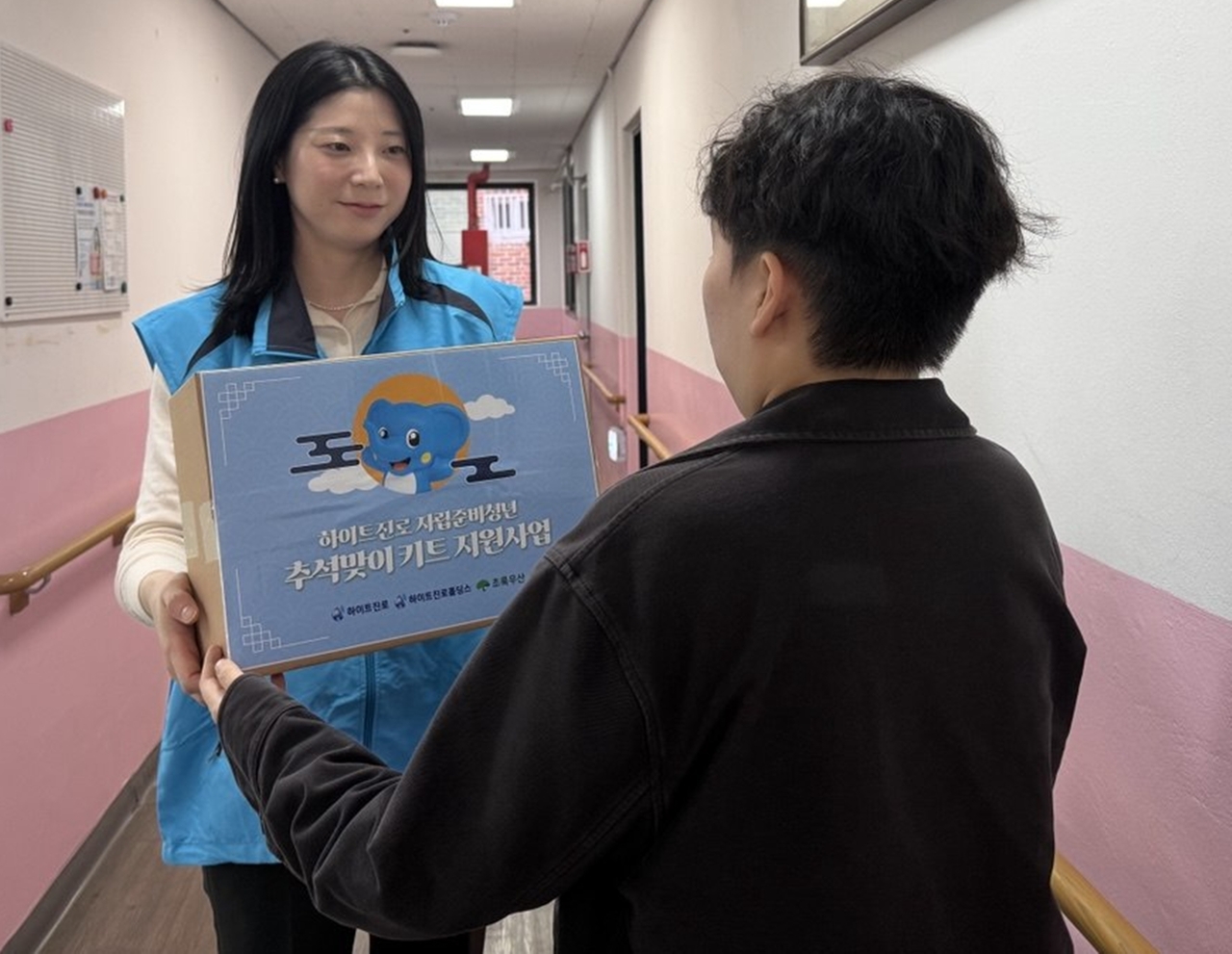 A Hitejinro official delivers a chuseok care package to a youth aging out of foster care as part of the companies' holiday outreach initiative. [Hite Jinro]