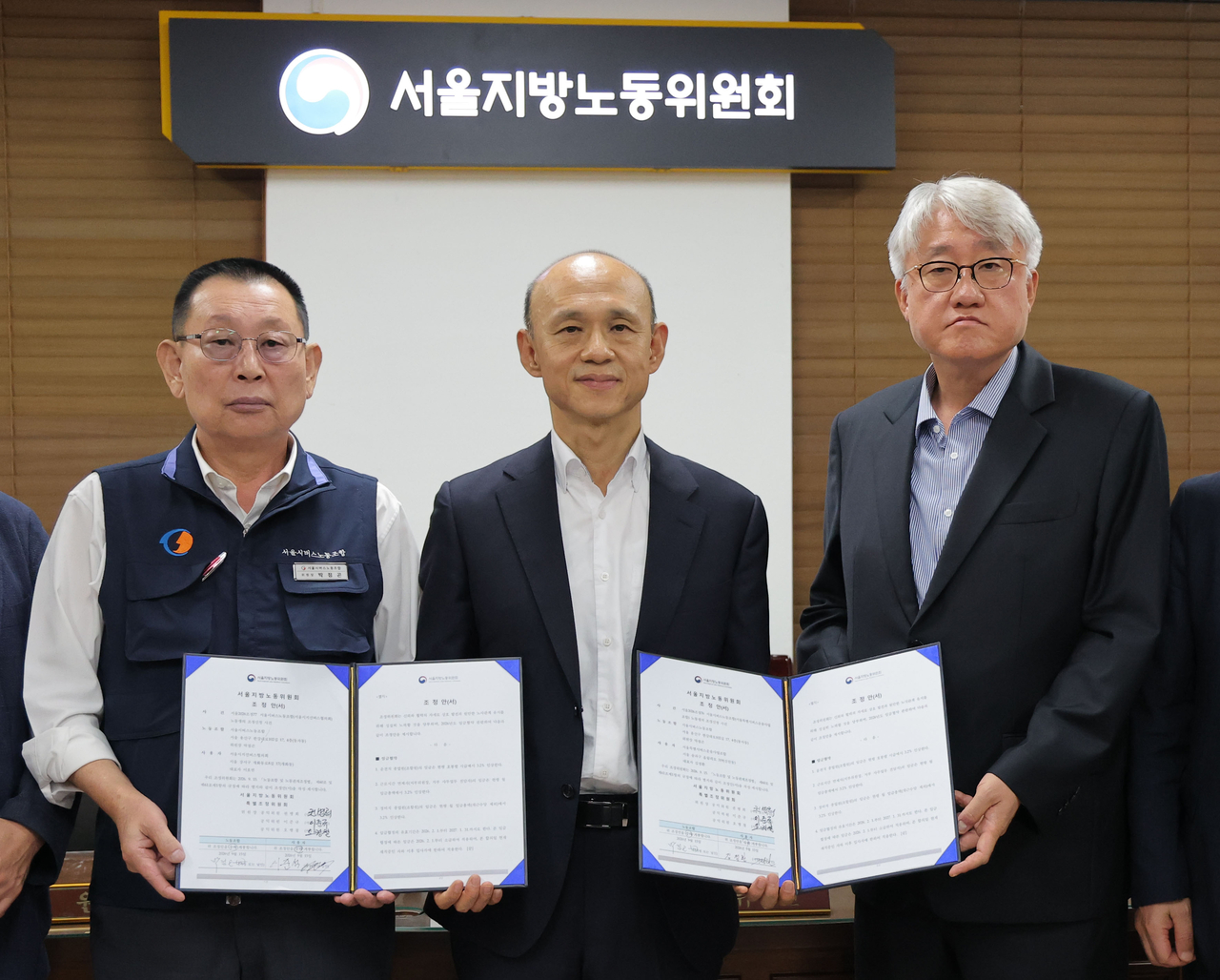 16일 서울 영등포구 서울지방노동위원회에서 열린 서울 시내버스 노사 2차조정회의에서 김정환(오른쪽) 서울시버스운송사업조합 이사장과 박점곤(왼쪽) 전국자동차노동조합연맹 서울시버스노동조합 위원장이 지노위 조정안에 서명한 뒤 기념촬영을 하고 있다. [연합]