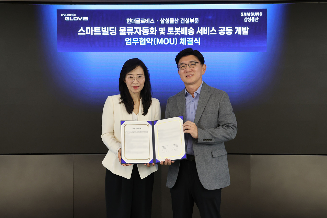 Han Kyu-heon, head of Hyundai Glovis's Future Innovation Technology Center (right), and Jo Hye-jeong, head of Samsung C&T's DxP division, pose for a photo after signing an MOU for the joint development of smart-building logistics automation and robot delivery services at Hyundai Glovis's headquarters in Seongdong-gu, Seoul, on Wednesday. [Hyundai Glovis]