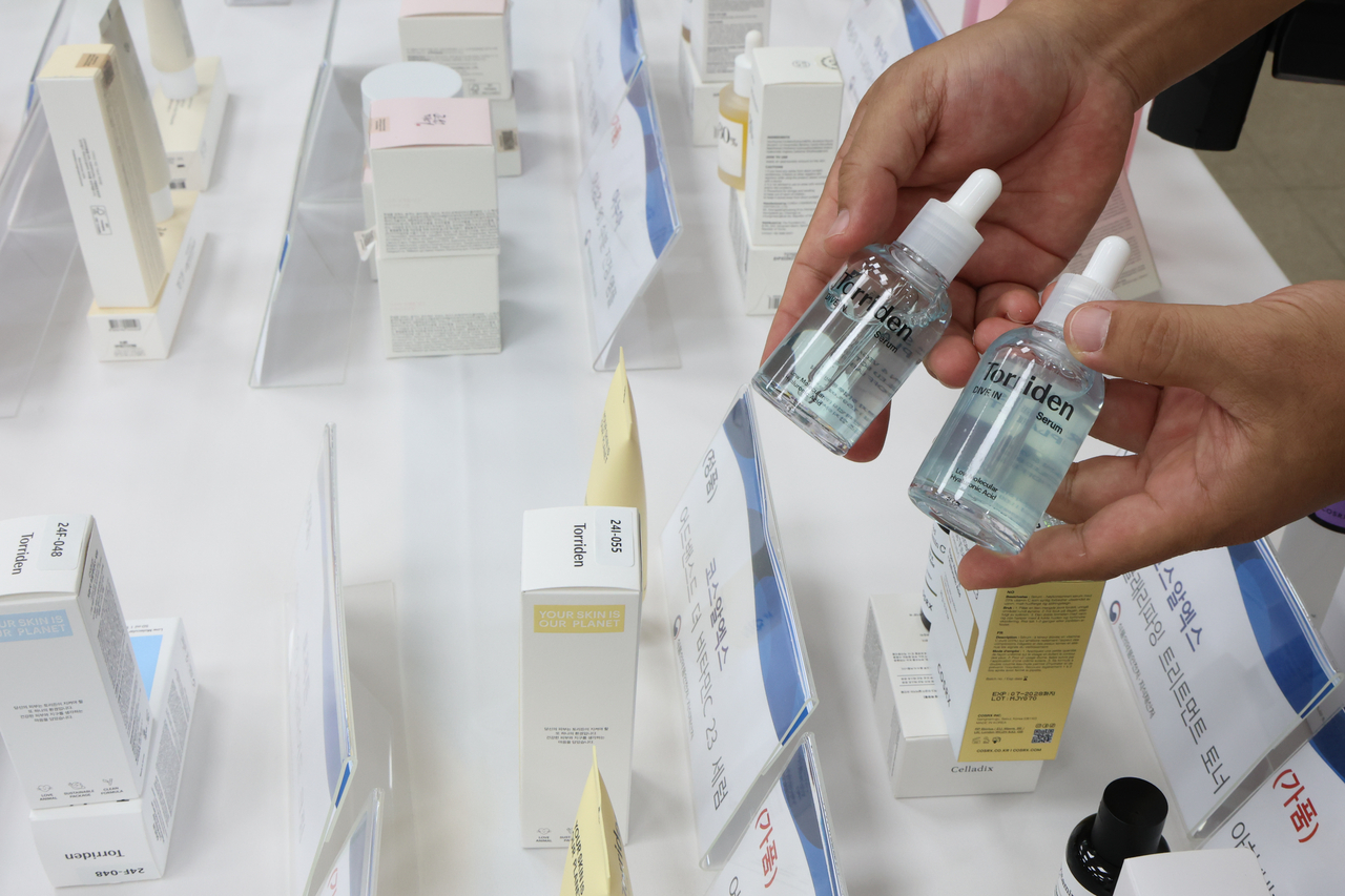 An official from the Regional Office of Food and Drug Safety compares a counterfeit cosmetic product with an authentic sample during a briefing in Yangcheon-gu, Seoul, Thursday. (Yonhap)