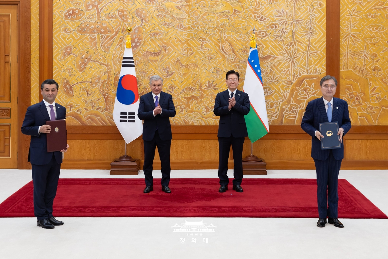 South Korean President Lee Jae Myung (second from right) and Uzbek President Shavkat Mirziyoyev (third from right) applaud as Korean Foreign Minister Cho Hyun (first from right) and his Uzbek counterpart Bakhtiyor Saidov exchange signed memoradums on Wednesday at Cheong Wa Dae in Seoul. (Ministry of Education)