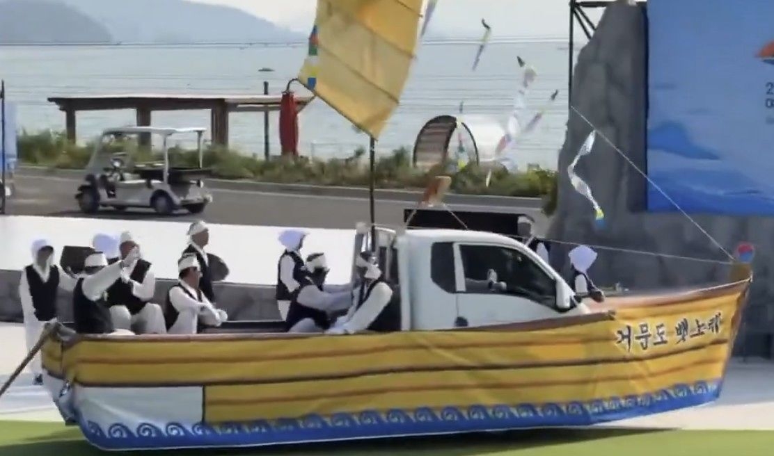 Performers recreate a traditional fishing scene on a fabric-covered truck made to look like a boat during a "Baennorae Folk Song" performance at the 2026 Yeosu World Island Expo on Tuesday. (X)