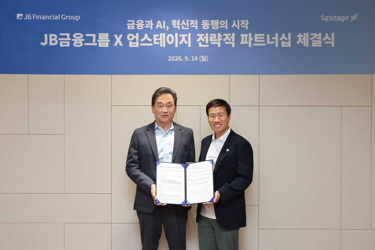 JB Financial Group Chairman Kim Ki-hong (left) poses for a photo with Upstage CEO Kim Sung-hoon after the two companies signed a strategic partnership for finance and AI technology and project cooperation on Monday. [JB Financial Group]